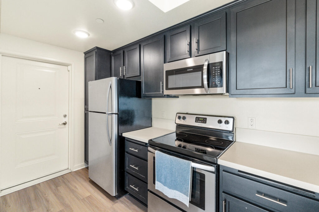 Kitchen with white counters, black cabinets, and stainless steel appliances