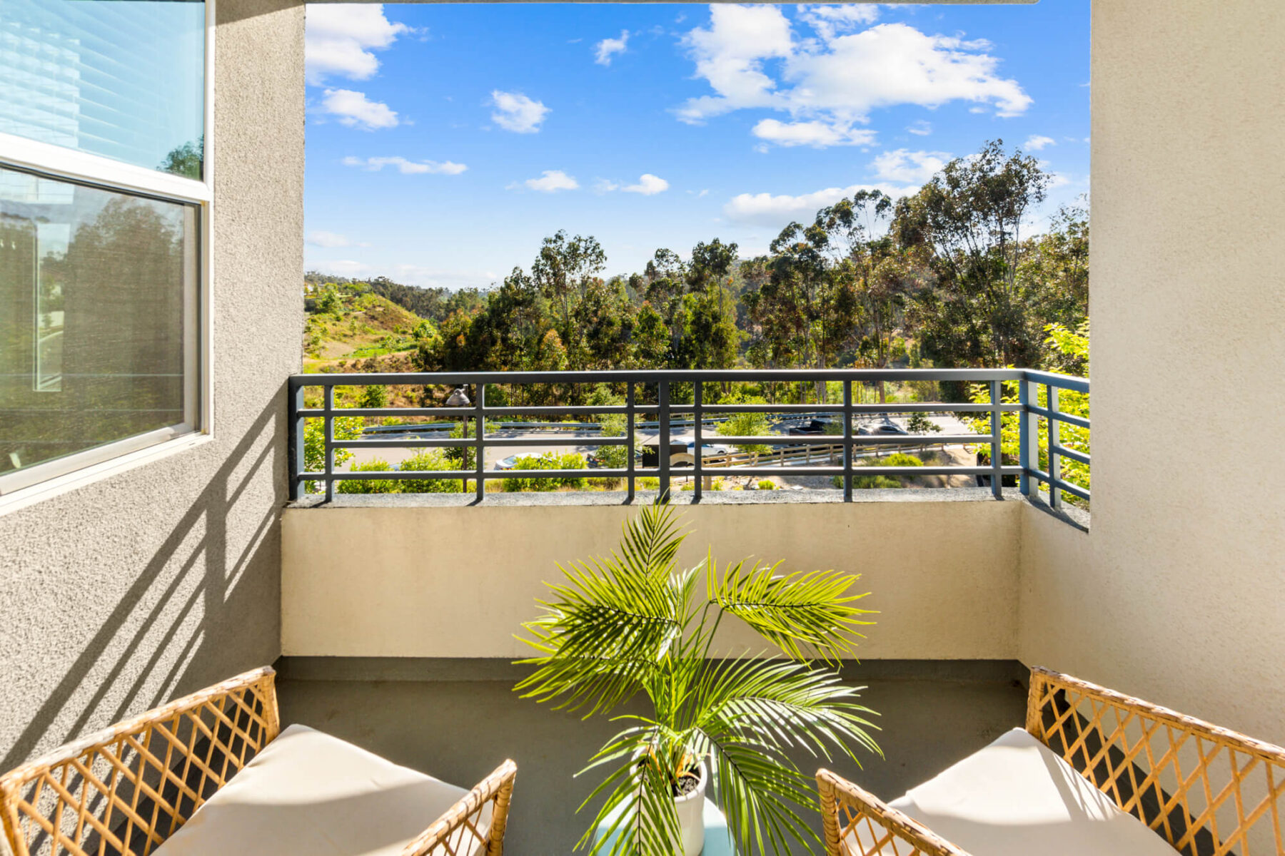 Private balcony with view of trees and a road in the distance