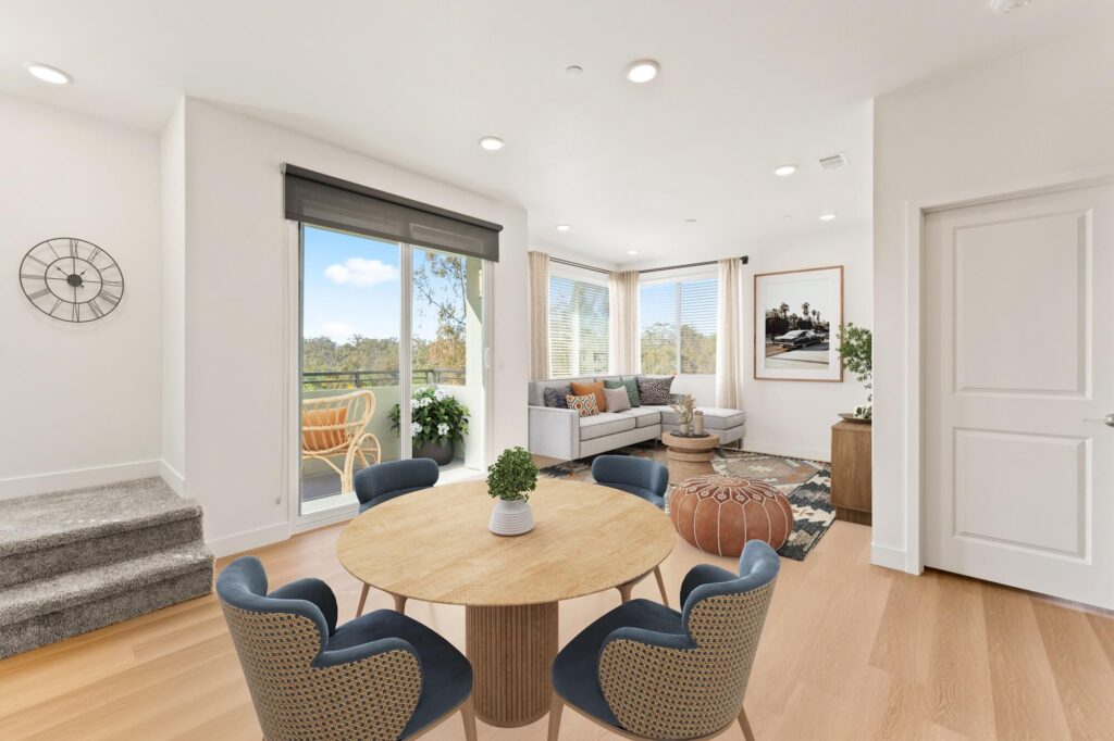 Dining room with open entry to living room, dining table, wood-style flooring, and designer lighting