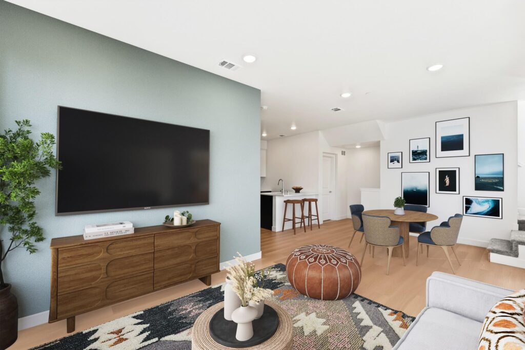 Living room with wood-style flooring, television, wall decor, and open entry to dining room and kitchen